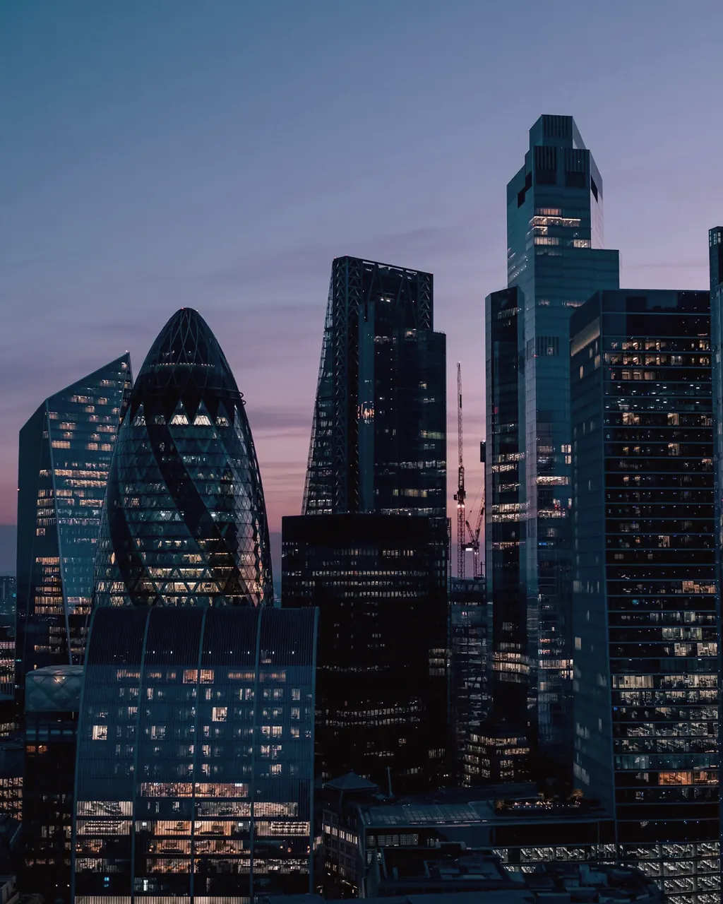 Axşam çağı London Sitisinin göydələnləri, o cümlədən 30 St Mary Axe və 22 Bishopsgate; ofis pəncərələrində işıq yanır